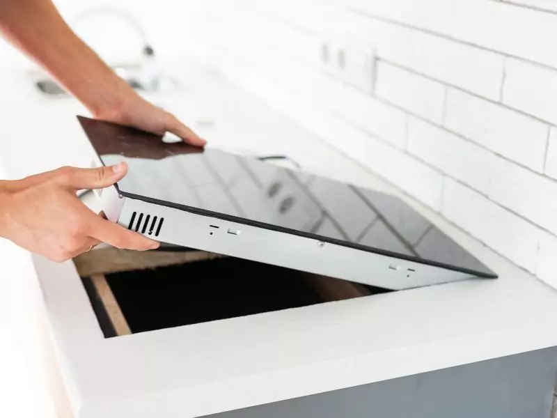 The technician is installing a cooktop