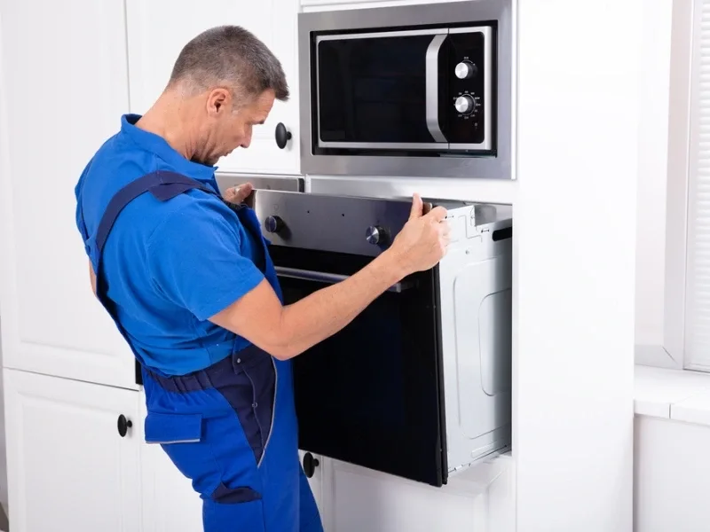 Appliance installation technician is working on wall oven