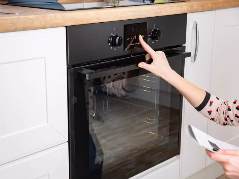 Woman setting up oven self-cleaning mode on oven control panel